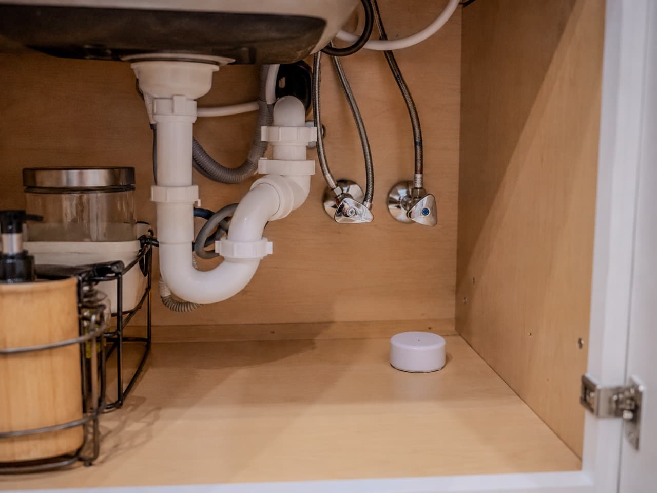Utility room with a water heater and plumbing lines for leak-risk monitoring.